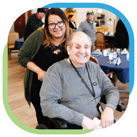 Smiling senior in a wheelchair and his assistant during a luncheon.