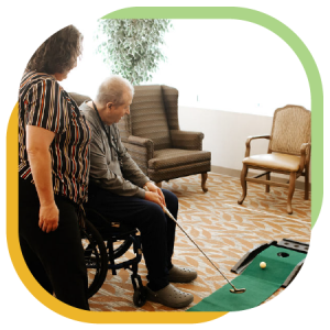 A senior in his wheelchair practices his putting skills on a portable putting green.